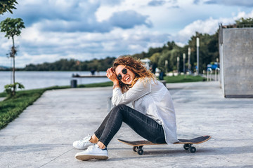 Cute girl with curly hair with skateboard in the park