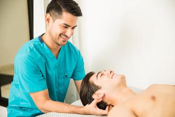 Obraz premium Physiotherapist Pressing Head Of Athlete In Clinic