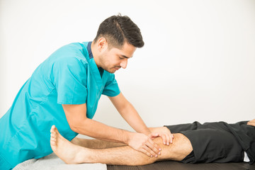 Man Getting Knee Treatment From Physiotherapist