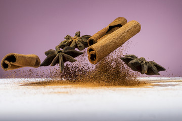Food levitating, star anise and cinnamon stick levitating on the white wooden table and pink background