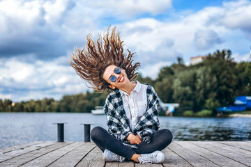 Cute girl with curly hair relaxing near lake