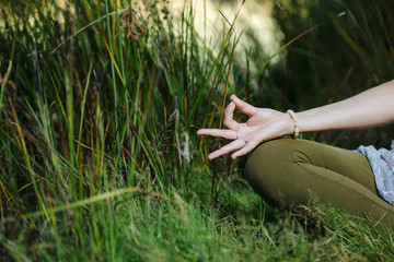 hands of young woman are folded in a special way of mudra into a yoga.  blurred background