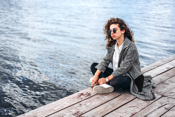 Cute girl with curly hair relaxing near lake