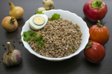 Plate with buckwheat on the table. Vegetables for cooking. Photo of food.