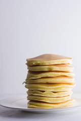 Pancakes on a white background. Many pancakes on a white plate with copy space. Delicious dish for breakfast