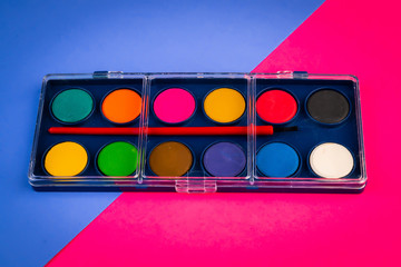 box with watercolors and brush on colored sheets of paper