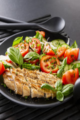 Vegetable salad and grilled chicken on a black background. Healthy food. Diet.