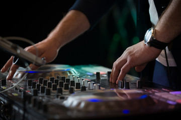 Closeup of DJ's hands mixing music at disco