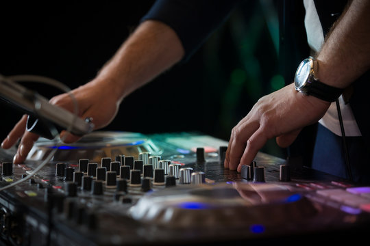 Closeup of DJ's hands mixing music at disco