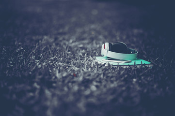 Hands and headphones are placed next to each other in green grass and moody music. Concepts of...