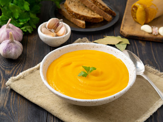 pumpkin puree, mashed of roasted pumpkin in a white plate on a dark wooden background, side view
