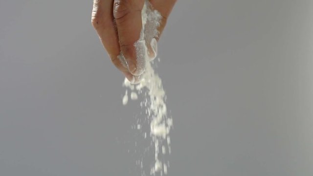 Baker's hands throwing the flour on a gray background in slow motion