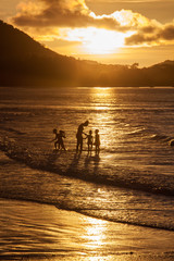 Fototapeta premium golden sunset with mother an children at the beach