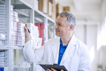 Portrait of mature male pharmacists working in modern drugstore