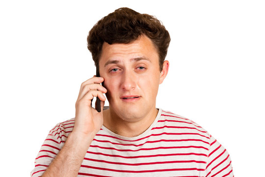 A young man heard the bad news on the phone and begins to cry. emotional man isolated on white background