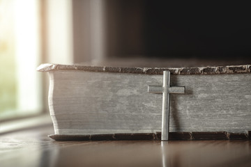 Silver cross with Bible on a wooden.