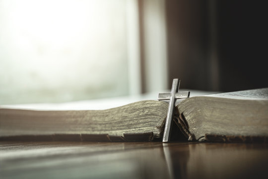 Close up Silver cross with the Bible on a wooden background. Holy book.