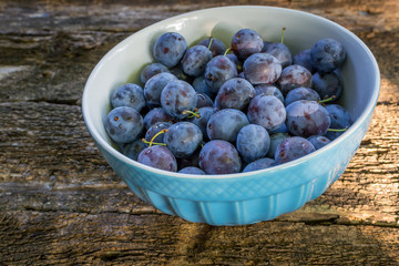 plums in bowl on wooden background