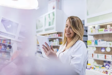 Photo sur Plexiglas Pharmacie Pharmacien travaillant avec un ordinateur tablette dans la pharmacie le tenant dans sa main tout en lisant des informations
