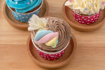 Tasty colorful cupcake isolated on wood background, close up.