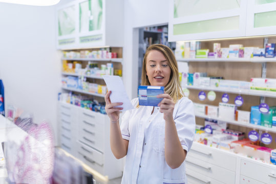 Beautiful smiling female pharmacist working in a pharmacy (or drugstore) with customer friendly attitude