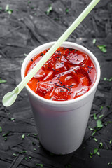 Cold tomato gazpacho soup in glass for summer with ice and basil on dark wooden background. Homemade food