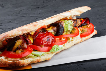 Vegetarian sandwich from grilled vegetables and fresh pita bread on dark wooden background. Shashlik or Shish kebab