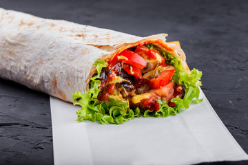 Vegetarian Burrito wraps from grilled vegetables and lettuce on dark wooden background. Healthy lunch