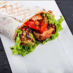Vegetarian Burrito wraps from grilled vegetables and lettuce on dark wooden background. Healthy lunch