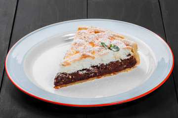 Delicious cake with berry jam and meringue on plate on dark wooden background, sweet food