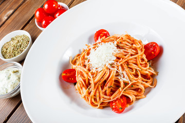 Pasta Spaghetti with olive oil, cheese, herbs and tomatoes on wooden background, Italian cuisine. Ingredients on table