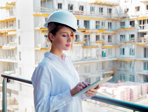 Young engineer woman with helmet and tablet on building.