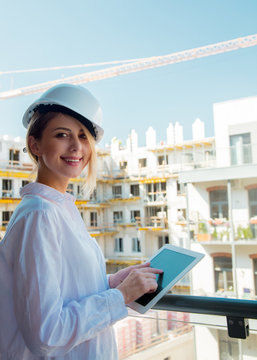 Young engineer woman with helmet and tablet on building.