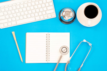 Top viwe of modern workplace with stethoscope and keyboard on blue table background. Flat lay...
