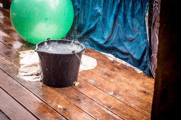 Rainy weather on the terrace in summer. The rain falls into the bucket and creates splashes.