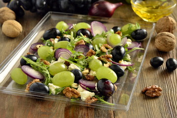 Salad with various grapes, goat cheese, purple onion, arugula and walnuts