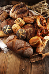 Different kinds of bread and bread rolls on board from above. Kitchen or bakery