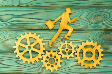 running worker, gears on a wooden background .. concept business, finance, workflow.