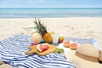 Beach picnic with lemonade and fruits (pineapple, grapefruit, kiwi, watermlon, cantaloupe, mango)