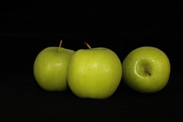 Single or group of apples including granny smith, golden delicious and royal gala on a black background.