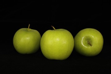 Single or group of apples including granny smith, golden delicious and royal gala on a black background.