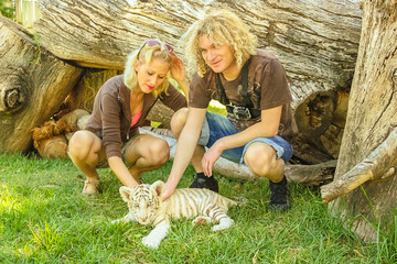 Happy young couple touching a little white tiger in Oudtshoorn, Western Cape, South Africa....