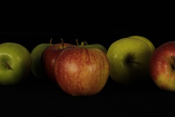 Single or group of apples including granny smith, golden delicious and royal gala on a black background.