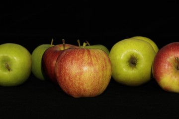 Single or group of apples including granny smith, golden delicious and royal gala on a black background.