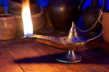 Ancient oil lamp burns on a wooden table