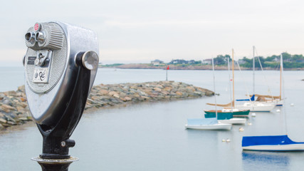 vintage tower viewer overlooking anchored sailboats and a rock breakwater at a small harbor in Massachusetts