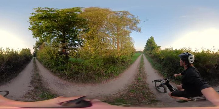 360VR video. Woman riding mountain bike at the sunset