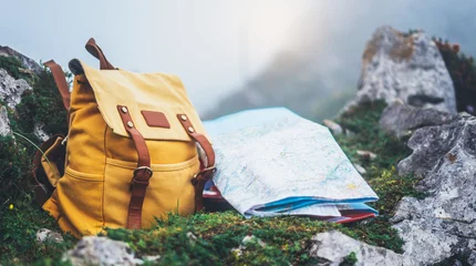 Foto op Plexiglas Hipster hiker tourist yellow backpack and map europe on background green grass nature in mountain, blurred panoramic landscape, traveler relax holiday concept, view planning wayroad in trip vacation © A_B_C