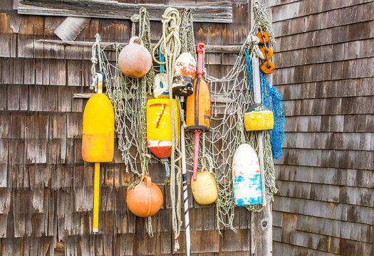 colorful lobster buoys and rope netting hanging on the wall of a weathered fishing shack in Massachusetts