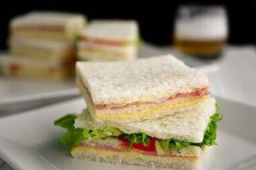 Sandwich with ham cheese tomato and lettuce with beer